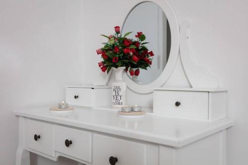a white dressing table with a mirror and red flowers at Villa Lipovac Trogir in Trogir