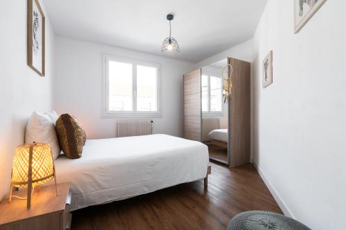 een witte slaapkamer met een bed en een spiegel bij DORMIR A CLERMONT-FERRAND - Safari in Clermont-Ferrand