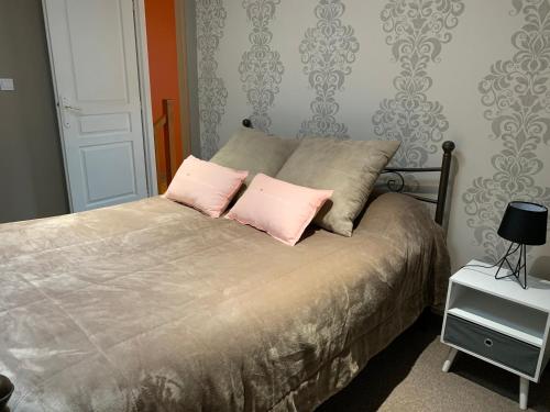 ein Schlafzimmer mit einem Bett mit zwei rosa Kissen in der Unterkunft La Maison Clémenso in Cluny