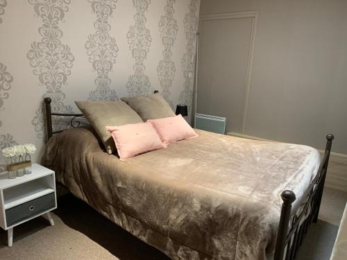 a bedroom with a bed with two pink pillows at La Maison Clémenso in Cluny