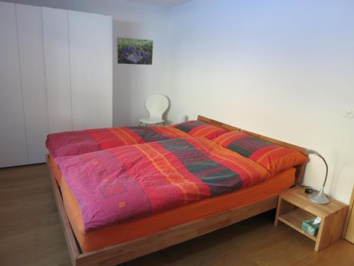 Una cama con una manta de colores encima. en Apartment Beeli en Splügen