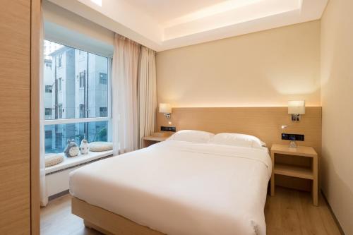 Un dormitorio con una gran cama blanca y una ventana en Yuwa Hotel, en Guangzhou