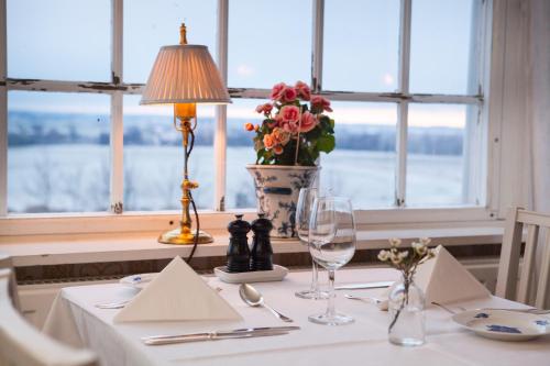 a table with a lamp and a vase with flowers at Ombergs Turisthotell in Ödeshög