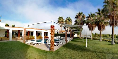 a house with a swimming pool and palm trees at Herdade da Diabroria - Agroturismo in Beja