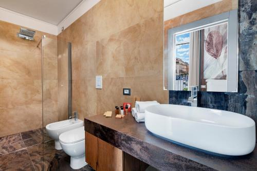 a bathroom with a tub and a toilet and a sink at Elys Suites in Sorrento