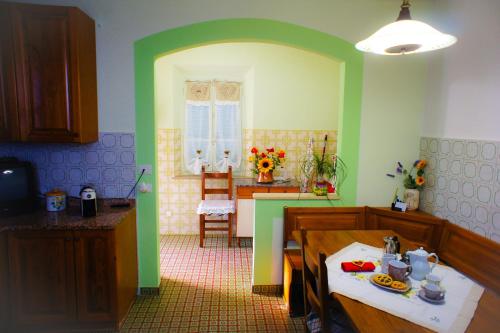 Casa Fonte di Bacco في سان مينياتو: مطبخ بجدران خضراء وطاولة وغرفة طعام