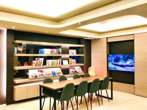 uma biblioteca com uma mesa e cadeiras e uma televisão em HUB HOTEL Tucheng em Tucheng