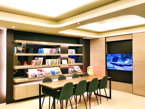 a library with a table and chairs and a television at HUB HOTEL Tucheng in Tucheng