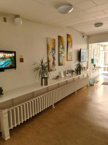 a waiting room with a long bench and paintings on the wall at Aarhus Hostel og Hotel in Aarhus