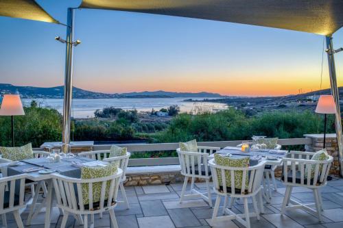 a patio with tables and chairs with the sunset in the background at Paros Agnanti Resort & Spa in Parikia
