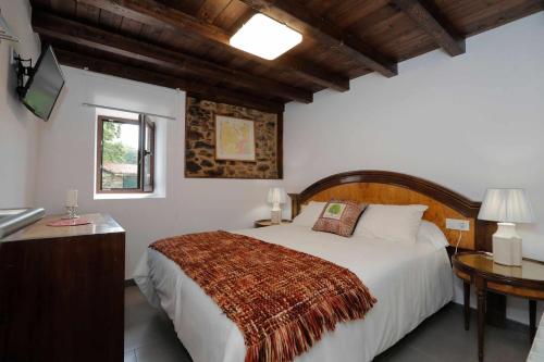 1 dormitorio con cama, mesa y TV en Casa Santa María en Melide