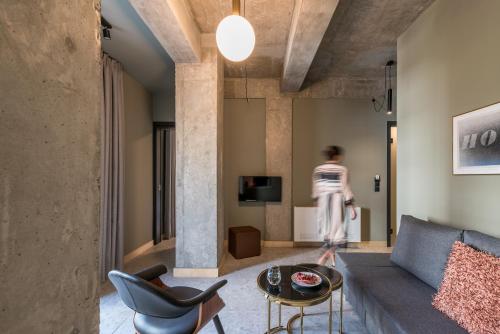 a woman walking through a living room with a couch and chairs at Cohort Koukaki in Athens