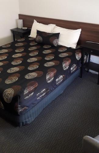 a bed in a hotel room with a black comforter at Daydream Motel and Apartments in Broken Hill