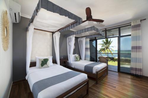 two beds in a room with a view of the ocean at Kena Beach Villas in Marumbi