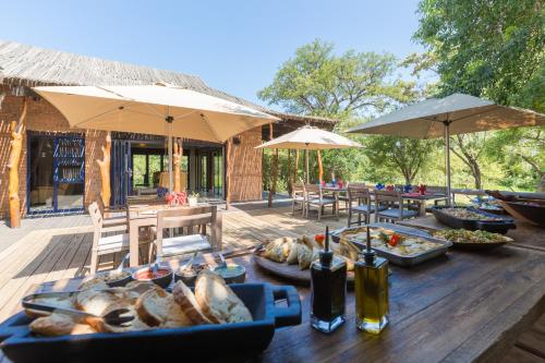 a table with food on a wooden deck with umbrellas at Baobab Ridge in Klaserie Private Nature Reserve