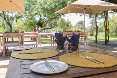 a wooden table with plates and utensils on it at Baobab Ridge in Klaserie Private Nature Reserve