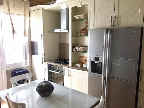 a kitchen with a white table and a refrigerator at Villa La Croisée des Chemins in Bray-Dunes