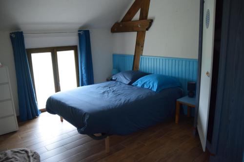 a bedroom with a blue bed and a window at Gïte de l Armance in Les Ventes