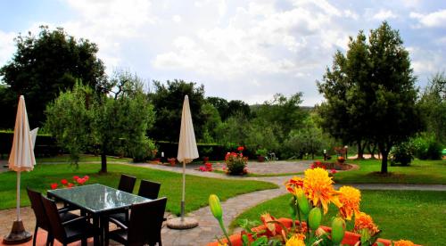 a table and chairs with umbrellas in a garden at Borgo Di Collelungo in Montaione