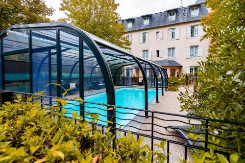 ein Pool in einem Glashaus neben einem Gebäude in der Unterkunft Hôtel Villa Flornoy Pornichet Baie de la Baule in Pornichet