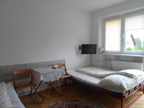 een slaapkamer met 2 bedden, een tafel en een raam bij Kwatery Pokoje Mira in Poznań