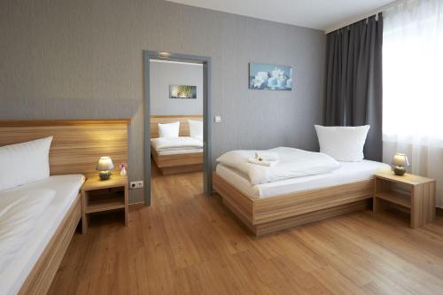 a hotel room with two beds and a mirror at Hotel Weimarer Berg in Apolda