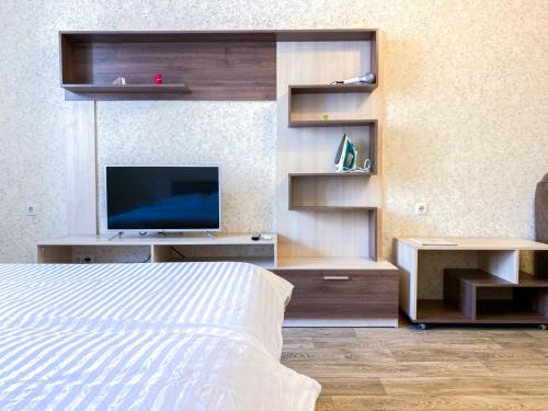 a bedroom with a bed and a tv and shelves at ApartPoltava Простора однокімнатна квартира в НОВОМУ будинку в самому серці Полтави, Банківський ЧЕК in Poltava