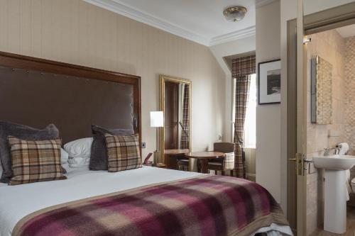 a bedroom with a large bed with a plaid blanket at Cairngorm Hotel in Aviemore