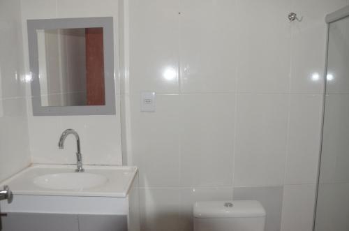 a white bathroom with a sink and a toilet at Vila Suítes Coliving in Vila Velha