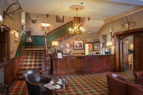 a lobby with a staircase and chairs and a table at Cairngorm Hotel in Aviemore