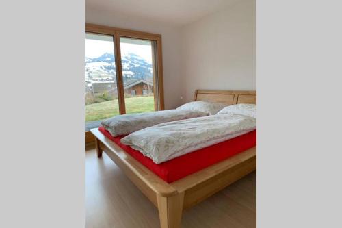 um quarto com uma cama e uma grande janela em Région de GSTAAD, charmant chalet duplex de 80m2 em Zweisimmen