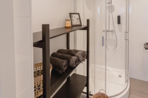 ein Badezimmer mit einem Regal mit Handtüchern und einer Dusche in der Unterkunft Madrid Suites in Maastricht