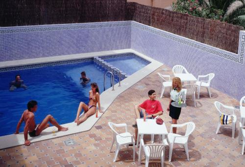 a group of people sitting around a swimming pool at BLUESEA Mediodia in El Arenal