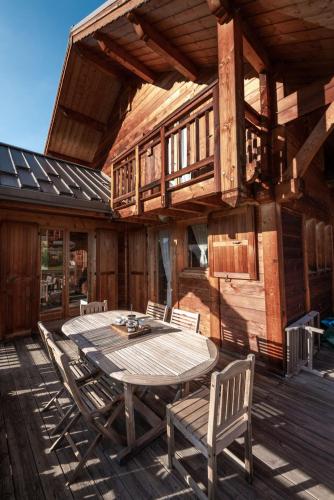 a wooden deck with a table and chairs on a house at Chalet Hibou, large chalet with mountain views and close to slopes in Saint-Chaffrey