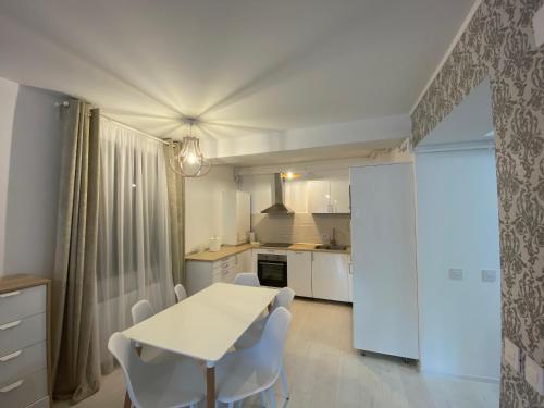 a kitchen with a white table and white chairs at Luxury Cosmo Apartments Sinaia in Sinaia