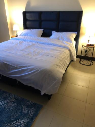 a bedroom with a large bed with white sheets and pillows at نزل المارينا - Marina Resident in King Abdullah Economic City