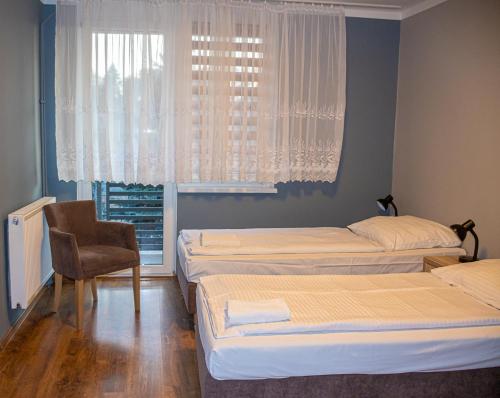 a room with three beds and a chair and a window at Olimpik Park in Słubice