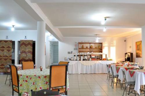 a dining room with tables and chairs and a kitchen at Hotel Carolina 2- próximo ao hospital Regional, hospital Mario Palmério, Hospital São Marcos in Uberaba