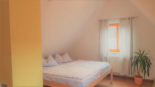 a bedroom with a bed with white sheets and a window at Ferienwohnung Abel in Heideck