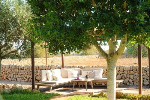 a white couch sitting under a tree next to a table at Agroturismo Finca Sa Tanca in Cala d´Or