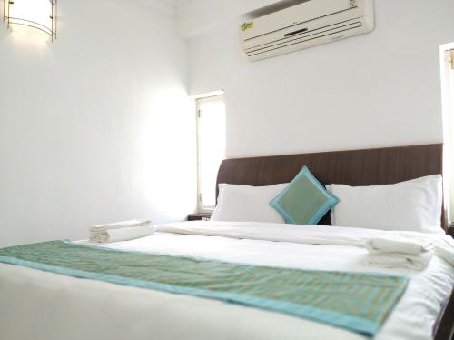 a bedroom with a bed with white sheets and blue pillows at Aum Hotel in Puttaparthi