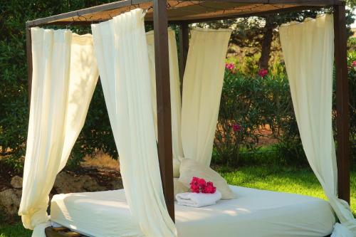 a canopy bed with white curtains and pink flowers on it at Agroturismo Finca Sa Tanca in Cala d´Or