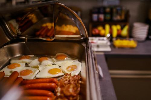 a tray of eggs and sausage in a sink at Sóház Panzió és Apartmanház in Szolnok