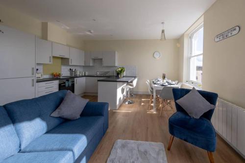 ein Wohnzimmer mit einem blauen Sofa und einer Küche in der Unterkunft Apartment 5, Isabella House, Aparthotel, By RentMyHouse in Hereford