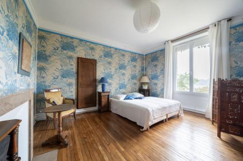 um quarto com papel de parede azul, uma cama e uma janela em Gîte de la Bove em Bouconville-Vauclair