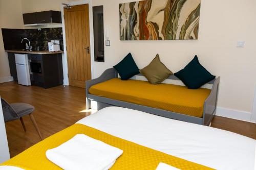 ニューカッスル・アポン・タインにあるAA Alexander Houseのベッド2台と黄色のソファが備わる客室です。