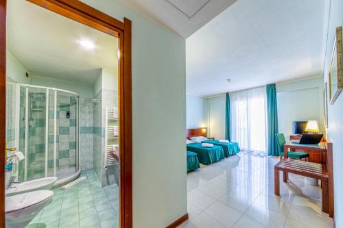 a bathroom with a shower and a bedroom with a bed at Hotel Le Torri in Arborea 
