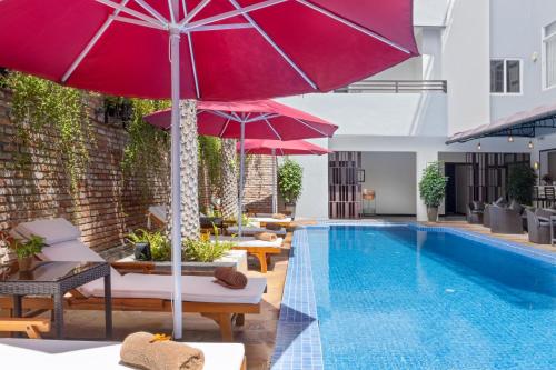 a pool with umbrellas and lounge chairs next to a swimming pool at Anik Boutique Hotel & Spa on Norodom Blvd in Phnom Penh