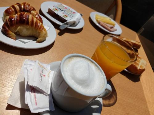 einen Tisch mit einer Tasse Kaffee, einem Croissant und einem Getränk in der Unterkunft Hotel Cristoforo Colombo in Buenos Aires