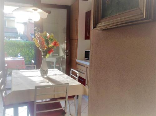 a dining room table with a vase of flowers on it at RESORT VILLAGE AQUA MARINA FAMILY - Daily Rooms Tidying - CocktailsBar- Pet Friendly - with Hypermarket - Delivery Restaurant-Pizzeria - Room Breakfast with supplement - Ultra Fast Wi-Fi - Play Area for children - Olympic Swimming Pool - Parking in Caorle